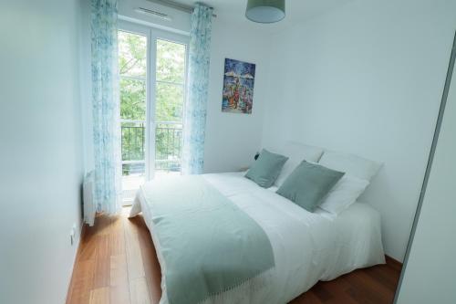 a white bed in a room with a window at Appartement 7 personnes - Disneyland Paris in Serris