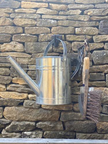 a metal bucket hanging on a stone wall at Jasmine Cottage, Upper Slaughter, Cotswolds in Cheltenham