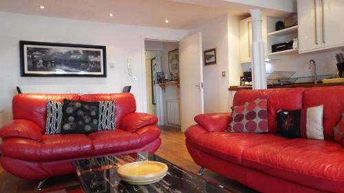 a living room with two red leather couches and a table at Mill Wharf in Berwick-Upon-Tweed