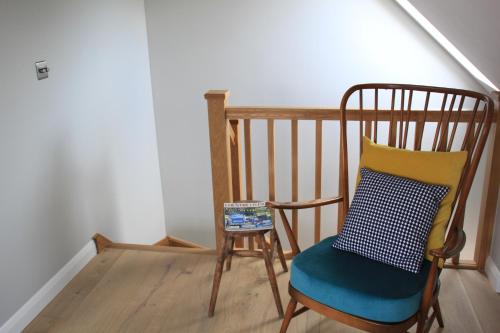 a wooden chair with a pillow and a stool at Charming and luxury retreats on our farm in Billingshurst