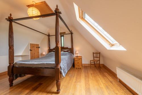 a bedroom with a canopy bed in a attic at Jay Barn - Ash Farm Cotswolds in Stow on the Wold