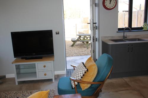 a living room with a tv and a chair at Charming and luxury retreats on our farm in Billingshurst