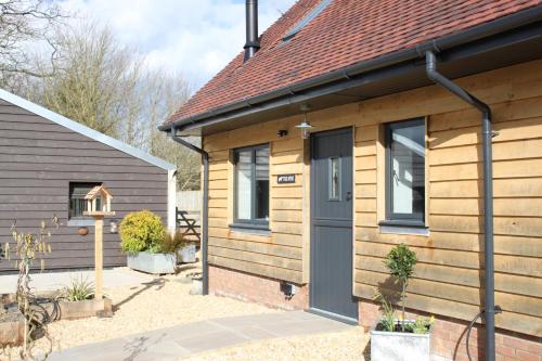a wooden house with a black door in a yard at Charming and luxury retreats on our farm in Billingshurst