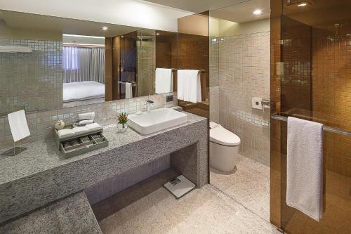 a bathroom with a sink and a toilet and a mirror at The Landis Taipei in Taipei