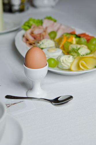 a egg and a spoon next to a plate of food at Hotel Dębowe Wzgórze Wellness & Spa in Jarnołtówek