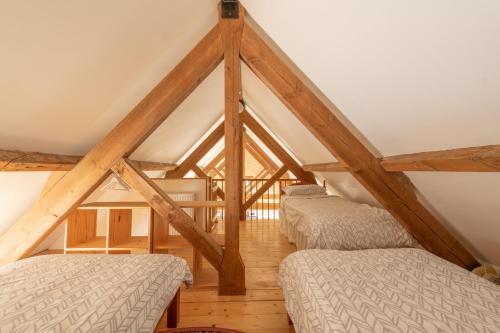 a attic room with two beds and wooden beams at The Oaks - Ash Farm Cotswolds in Stow on the Wold