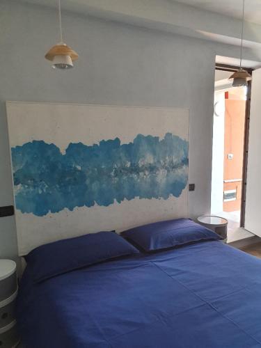 a bedroom with a blue bed with a painting on the wall at Il Giramondo in Busca
