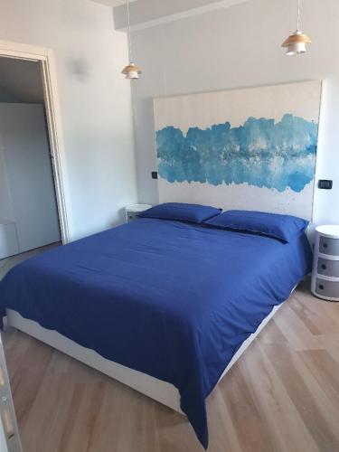 a bedroom with a blue bed with a painting on the wall at Il Giramondo in Busca