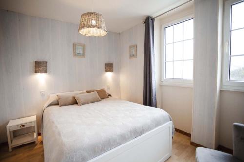 a bedroom with a white bed and two windows at Résidence Le Roc Fleuri in Saint Malo