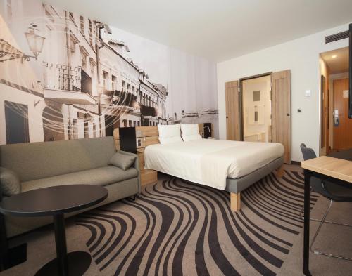 a hotel room with a bed and a couch at Novotel Vilnius Centre in Vilnius