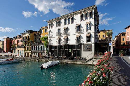 a boat in the water in front of a building at Hotel Bell'arrivo by Dori in Peschiera del Garda