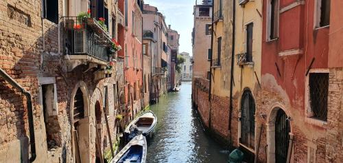 a canal with two boats in an alley between buildings at Cà Sant'Angelo in Venice