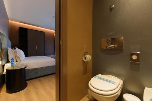 a bathroom with a toilet and a bed at Hotel Bell'arrivo by Dori in Peschiera del Garda