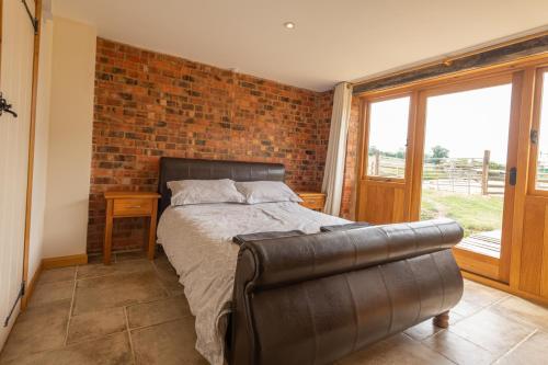 a bedroom with a bed and a brick wall at Mill Cottage 2 - Ash Farm Cotswolds in Stow on the Wold