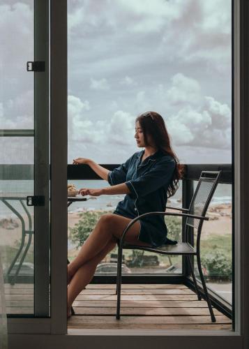 une femme assise sur une chaise sur un balcon dans l'établissement Sasa Nor Lamour B&B, à Eluan