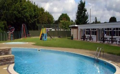 a large swimming pool in a park with a playground at Broadside Chalet Park No 90 in Norwich