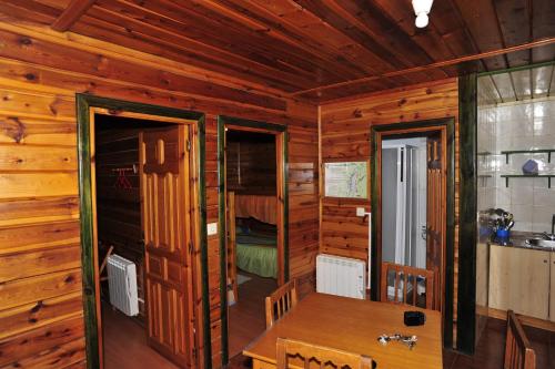 a wooden cabin with a table and a bedroom at Cabañas La Toma del Agua in Riópar