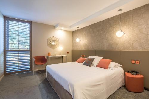 a bedroom with a large white bed and a window at Hôtel Restaurant du Château de la Tour in Béguey