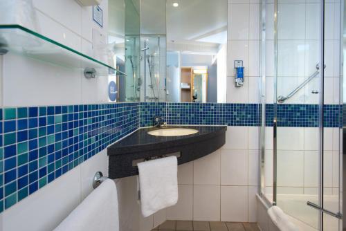 uma casa de banho com um lavatório e um chuveiro em Holiday Inn Express Cambridge, an IHG Hotel em Cambridge