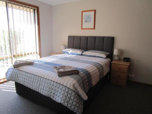 a bedroom with a large bed and a large window at Anchorbell Holiday Apartments in Merimbula