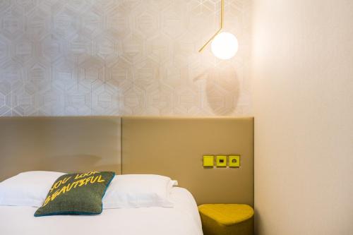 a bedroom with a white bed and a yellow stool at Hôtel Restaurant du Château de la Tour in Béguey