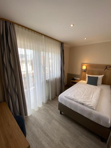 ein Schlafzimmer mit einem Bett und einem großen Fenster in der Unterkunft Hotel Rosenbusch in Großheubach