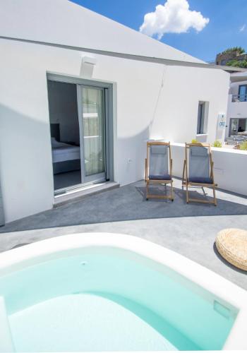 a white house with two chairs and a swimming pool at Oro Suites in Kinion