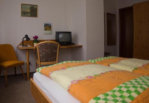 a bedroom with two beds and a desk with a television at Landgasthof Kemter in Dröbischau