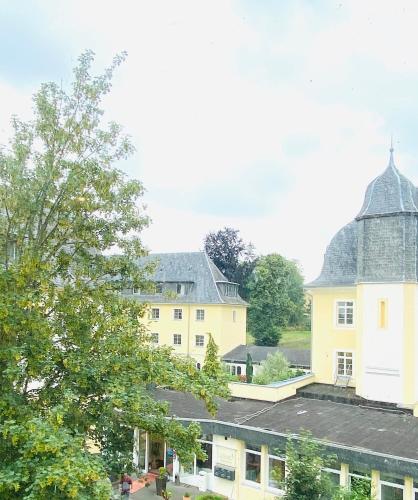 a large yellow building with a domed roof at Schlosshotel Domäne Walberberg in Bornheim