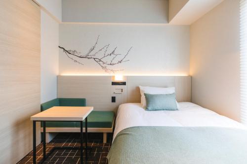 東京にあるホテル八重の翠東京のベッドとテーブルのある小さな寝室