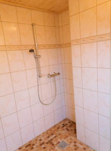 a shower in a bathroom with white tiles at Pension Weinig in Gersfeld