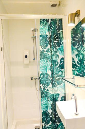 a bathroom with a shower with green leaves wallpaper at Family Hotel Kooyk in Amsterdam