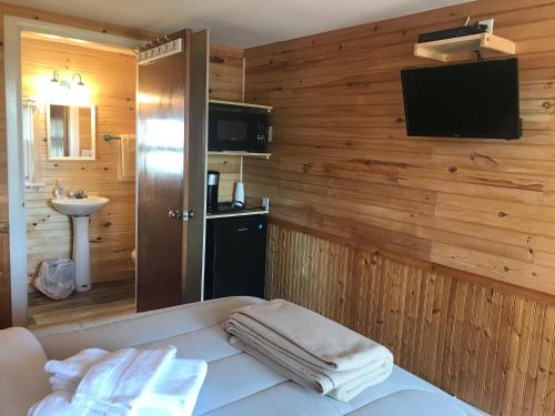 a bathroom with wooden walls and a tv on a wall at The Coastal Cabins in New Brunswick in Cape Tormentine