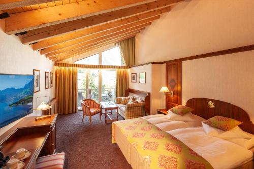 a hotel room with a bed and a living room at Hotel Sonne in Zermatt