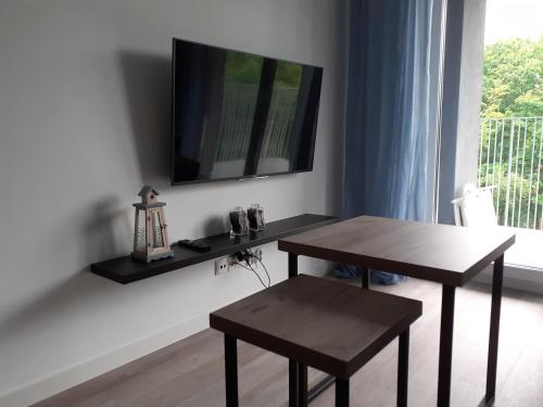 sala de estar con 2 mesas y TV en la pared en Apartament Kora en Kołobrzeg