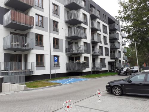 un coche aparcado frente a un gran edificio en Apartament Kora en Kołobrzeg