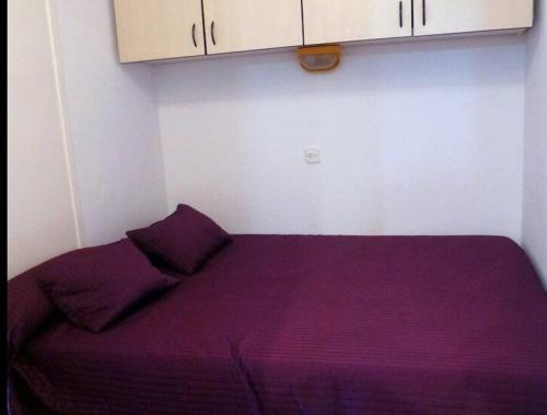 um quarto com uma cama com lençóis e armários roxos em ARGONAVIS BLUE em L'Estartit