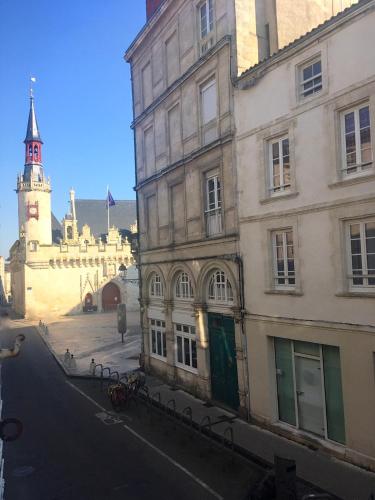 un bâtiment avec une tour d'horloge dans une rue dans l'établissement Hôtel de Ville 2 avec Parking, à La Rochelle