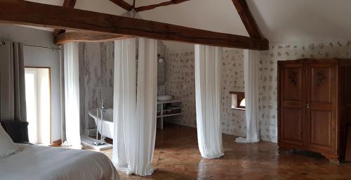 ein Schlafzimmer mit einem Bett und ein Badezimmer mit einem Waschbecken in der Unterkunft La Maison Josnes de Mady in Josnes