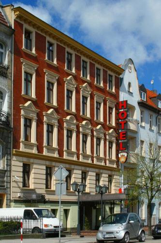 a large brick building with a sign in front of it at W Starej Kamienicy in Gniezno