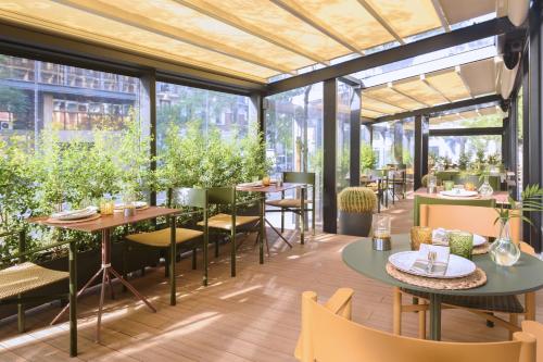 a restaurant with tables and chairs and windows at Melia Madrid Serrano in Madrid