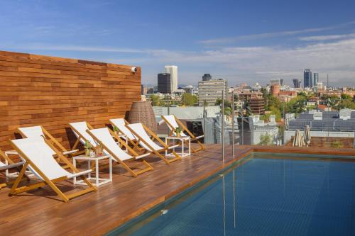 un grupo de tumbonas en la azotea con piscina en Melia Madrid Serrano en Madrid