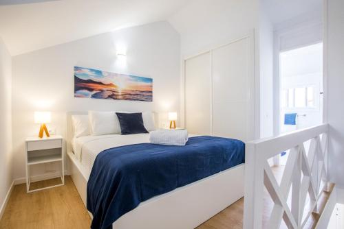 een witte slaapkamer met een bed met een blauwe deken bij Parque Santiago 1 Duplex 2A014 in Playa de las Americas