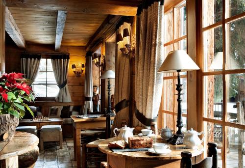 a room with wooden walls and tables and windows at Les Fermes de Marie in Megève