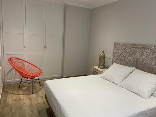 a bedroom with a bed and a red chair at Apartamentos, Brisa del Norte in Isla