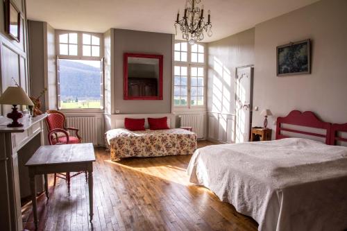 a bedroom with a bed and a couch and windows at Chambres d'hôtes de charme Le Pradel in Monceaux-sur-Dordogne