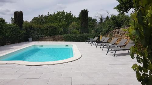 a swimming pool with lounge chairs and a row ofitureshiba at GITE DE LA GARÈNE in Grillon