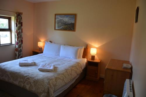 1 dormitorio con 1 cama con 2 toallas en Amber Cottage en Killarney