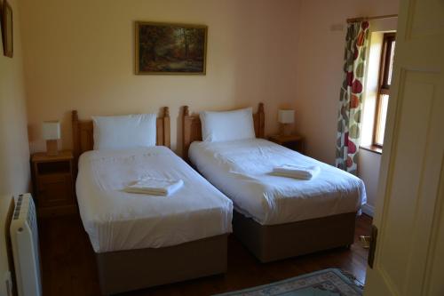 sypialnia z dwoma łóżkami i ręcznikami na nich w obiekcie Amber Cottage w Killarney