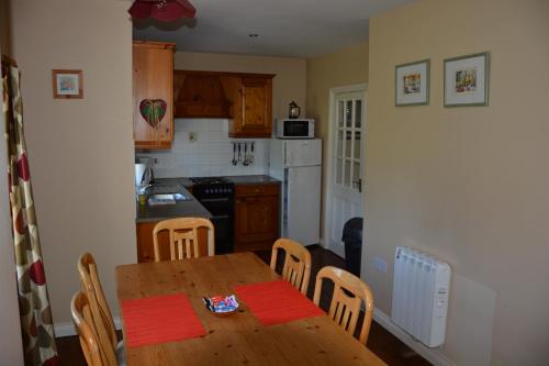 cocina con mesa de madera, mesa y sillas en Amber Cottage en Killarney